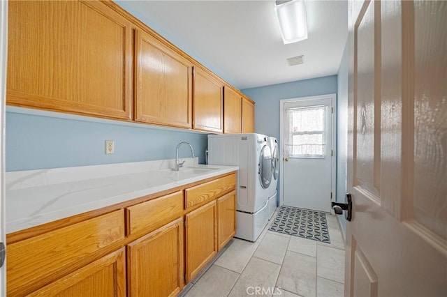 clothes washing area featuring cabinet space, visible vents, separate washer and dryer, and a sink