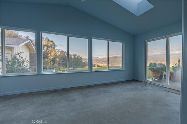 spare room with concrete floors, lofted ceiling with skylight, and baseboards