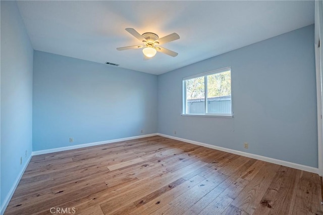 unfurnished room with baseboards, a ceiling fan, visible vents, and hardwood / wood-style flooring
