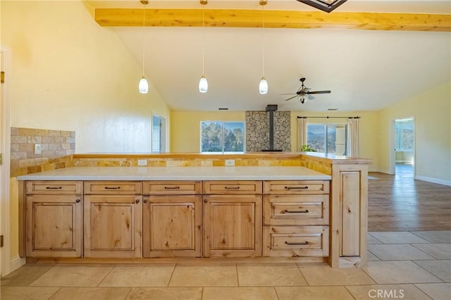 kitchen featuring a wood stove, plenty of natural light, vaulted ceiling with beams, and a ceiling fan