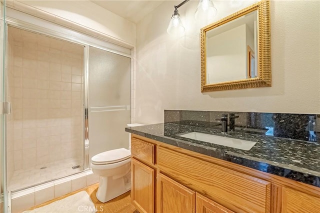 bathroom with toilet, a stall shower, and vanity