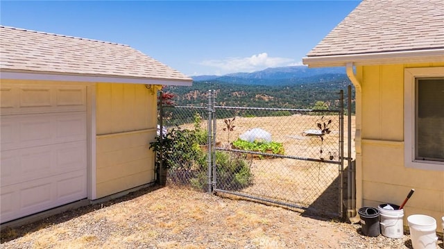 view of yard featuring a mountain view, fence, a gate, and a garage