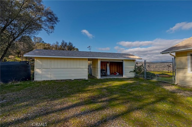 rear view of property with a yard, fence, an outdoor structure, and a gate