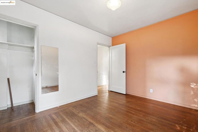 unfurnished bedroom with dark hardwood / wood-style flooring and a closet