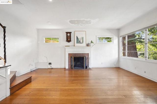 unfurnished living room with a brick fireplace and light hardwood / wood-style flooring