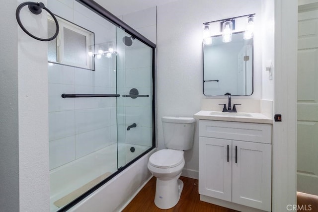 full bathroom with vanity, hardwood / wood-style floors, shower / bath combination with glass door, and toilet