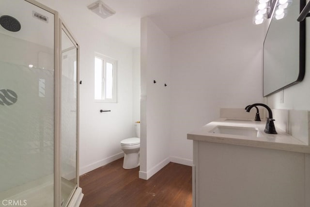 bathroom featuring hardwood / wood-style flooring, toilet, vanity, and a shower with shower door