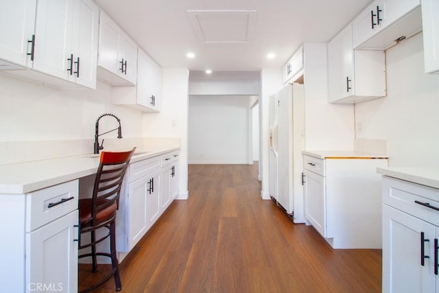 kitchen with white refrigerator with ice dispenser, built in desk, and white cabinets