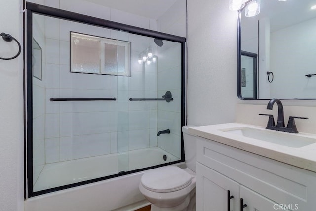 full bathroom with enclosed tub / shower combo, vanity, and toilet