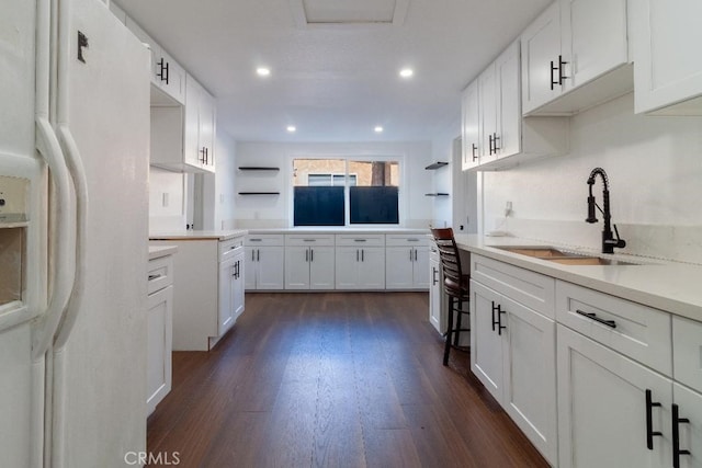 kitchen featuring white cabinetry, sink, white refrigerator with ice dispenser, and dark hardwood / wood-style flooring