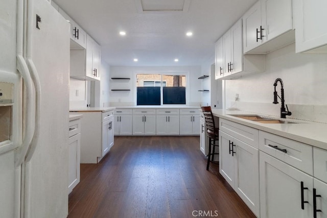 kitchen with white cabinetry, white refrigerator with ice dispenser, sink, and dark hardwood / wood-style floors