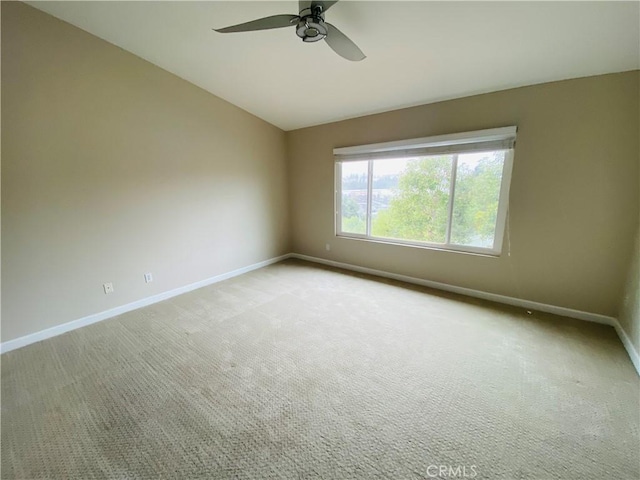 spare room with ceiling fan, light colored carpet, and vaulted ceiling