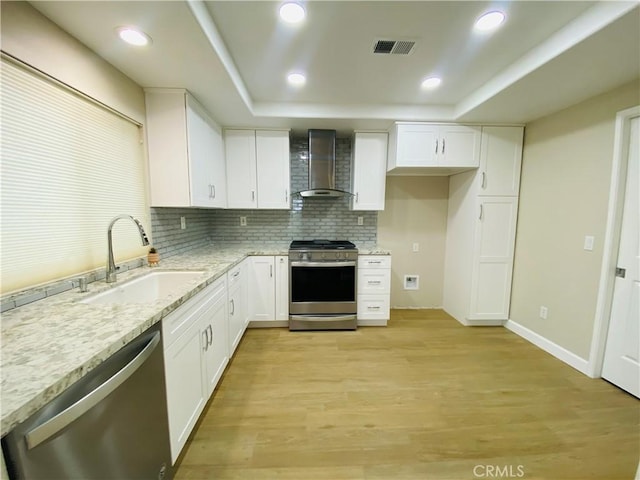 kitchen with white cabinetry, wall chimney range hood, stainless steel appliances, and sink