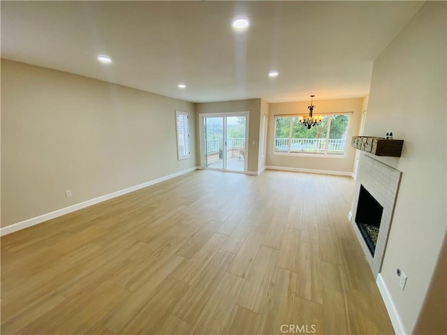 unfurnished living room featuring a notable chandelier and light wood-type flooring