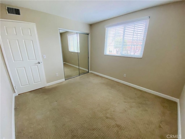 unfurnished bedroom featuring light colored carpet and a closet