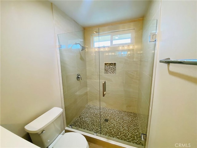 bathroom with a shower with door and toilet