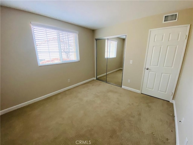 unfurnished bedroom featuring light colored carpet and a closet