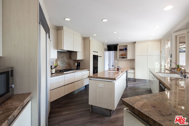 kitchen with dark hardwood / wood-style floors, sink, dark stone countertops, a kitchen island with sink, and black appliances