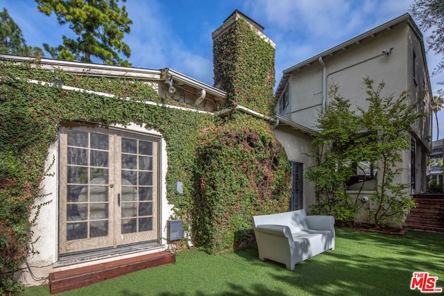 rear view of house featuring french doors and a lawn