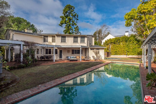 rear view of property with a yard, a pergola, an outdoor living space, and a patio