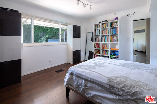 bedroom featuring crown molding, dark wood-type flooring, and track lighting