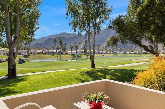 view of property's community featuring a water and mountain view and a lawn