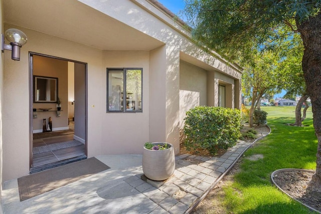 view of exterior entry featuring a patio and a yard