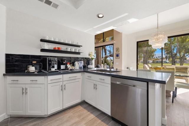 kitchen with sink, white cabinetry, hanging light fixtures, stainless steel dishwasher, and kitchen peninsula