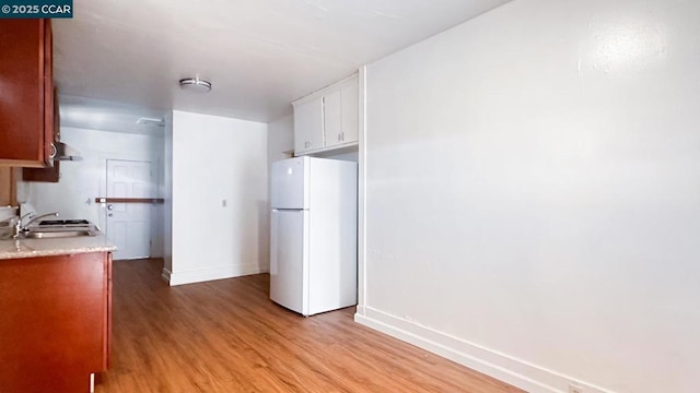 kitchen featuring white refrigerator, sink, light hardwood / wood-style flooring, and white cabinets