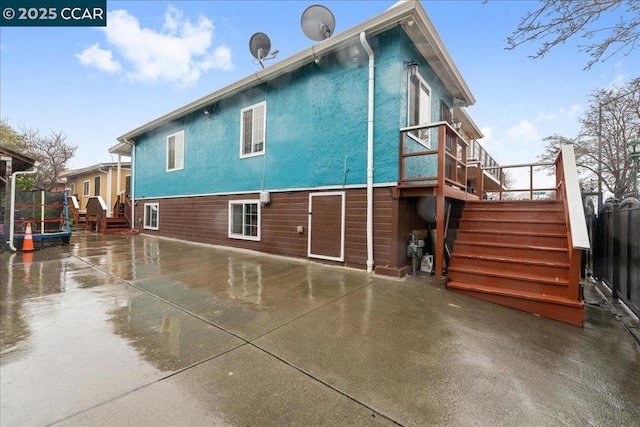 back of house with a trampoline and a patio area