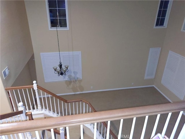 stairway with visible vents, a notable chandelier, and baseboards