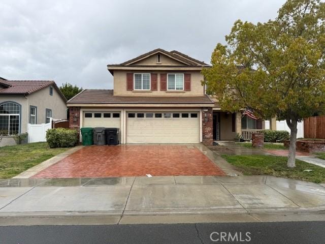 traditional-style home featuring fence, a front lawn, decorative driveway, and brick siding