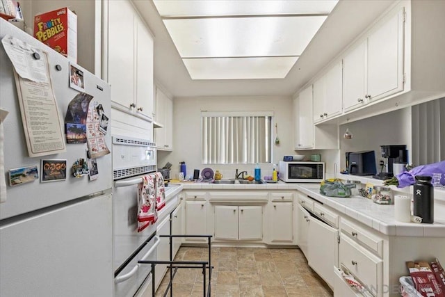 kitchen featuring sink, tile counters, white cabinets, and white appliances