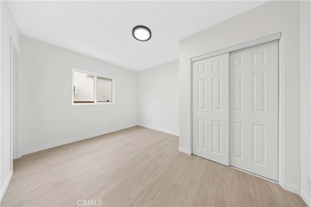 unfurnished bedroom featuring light hardwood / wood-style floors and a closet