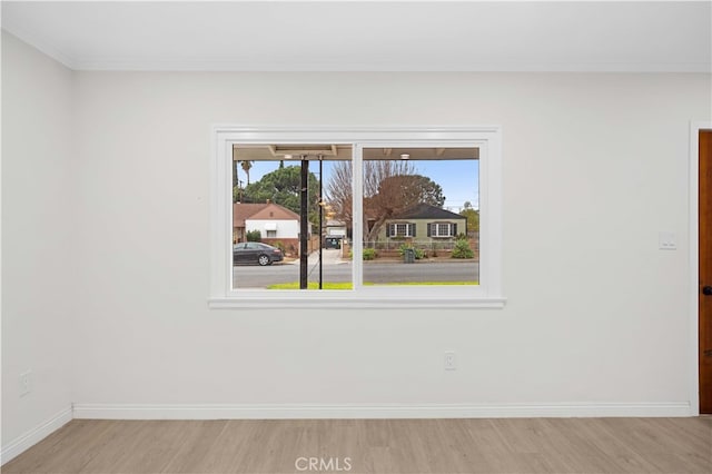 spare room featuring crown molding and light hardwood / wood-style flooring