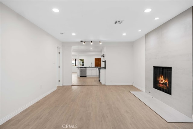 unfurnished living room with a large fireplace and light wood-type flooring