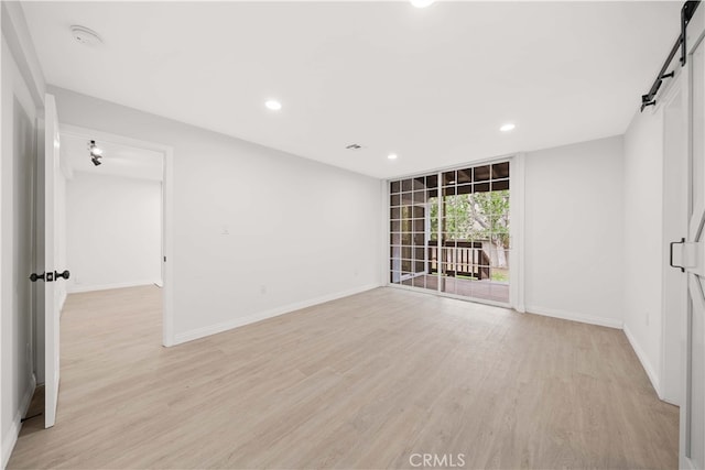 unfurnished room with light hardwood / wood-style flooring and a barn door