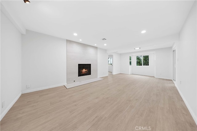 unfurnished living room with a large fireplace and light hardwood / wood-style floors