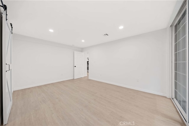 empty room featuring a barn door and light hardwood / wood-style floors