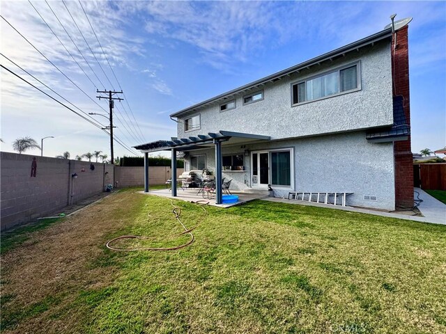 rear view of house with a fenced backyard, a yard, stucco siding, a pergola, and a patio area