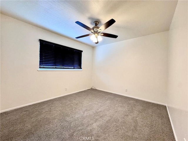 carpeted empty room featuring ceiling fan and baseboards