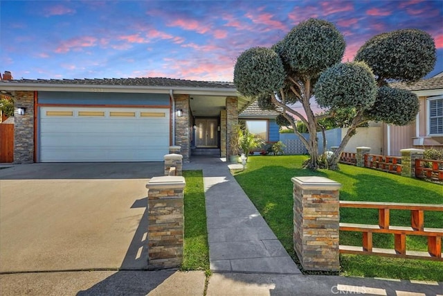 view of front of house with stone siding, a lawn, concrete driveway, and fence