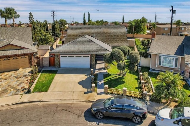 view of front of property featuring a garage, a tile roof, fence, driveway, and a front lawn