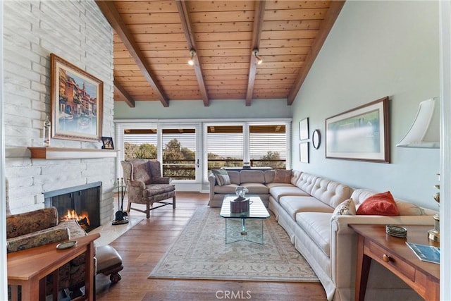 living room with wood ceiling, wood-type flooring, a stone fireplace, and beamed ceiling