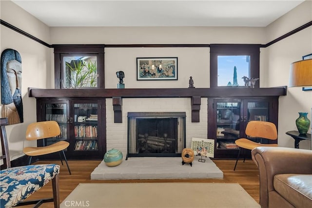 living room with wood-type flooring and a brick fireplace