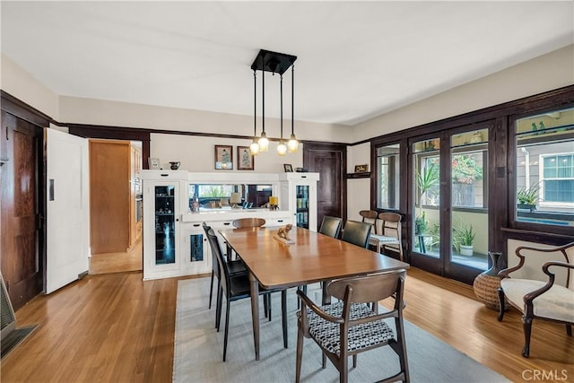 dining area with french doors, light hardwood / wood-style floors, and a wealth of natural light