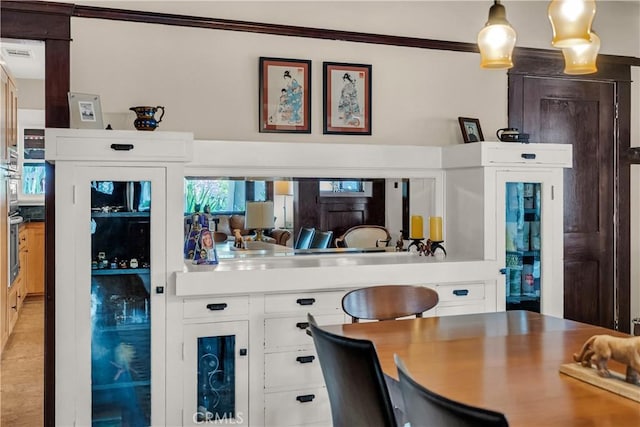 bar with crown molding, decorative light fixtures, and white cabinets