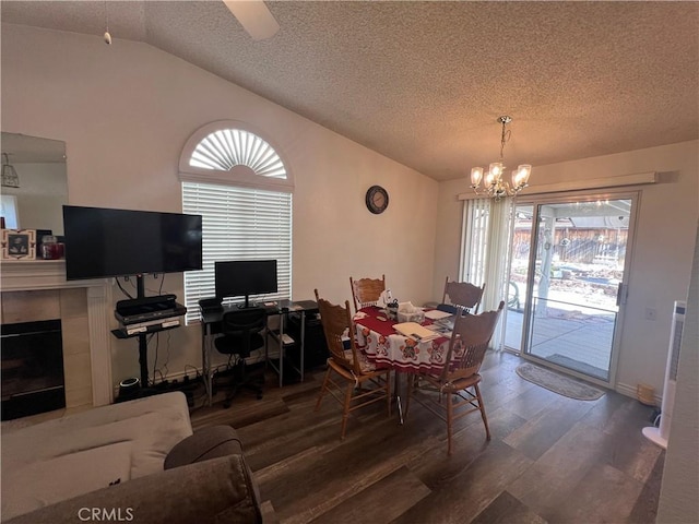 dining area featuring lofted ceiling, a chandelier, a textured ceiling, dark hardwood / wood-style flooring, and a tiled fireplace