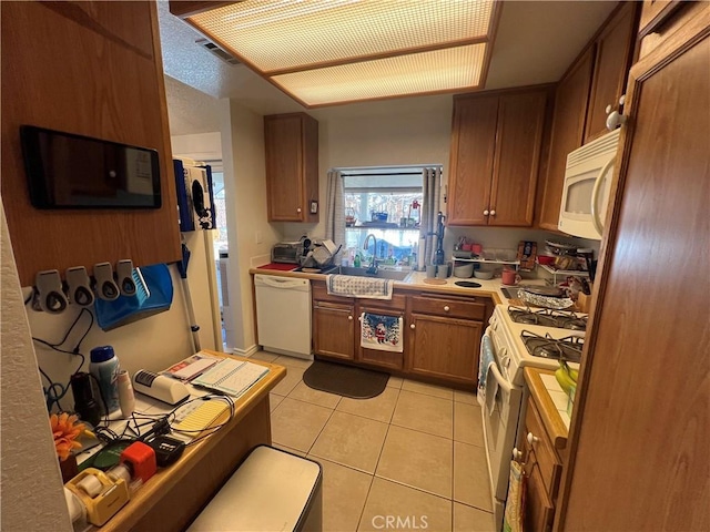 kitchen featuring white appliances, sink, and light tile patterned floors