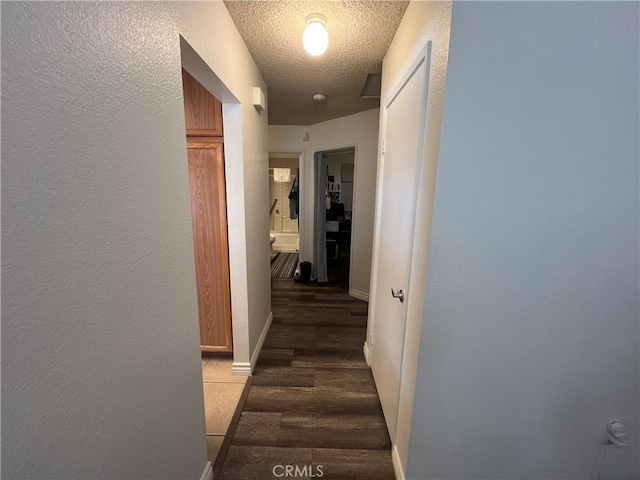 hallway featuring dark hardwood / wood-style floors and a textured ceiling